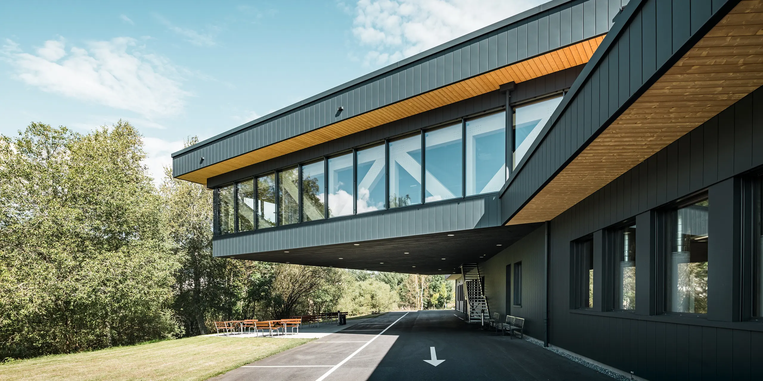Das Firmengebäude von KIF Parechoc in Le Brassus beeindruckt mit seiner auskragenden Architektur, großflächigen Verglasungen und einer markanten Fassade aus PREFA Sidings in P.10 Anthrazit. Die dunklen Aluminiumflächen setzen einen spannenden Kontrast zu den warmen Holzuntersichten und der natürlichen Umgebung. PREFA Aluminium überzeugt durch Langlebigkeit, Korrosionsbeständigkeit und einen besonders geringen Wartungsaufwand.