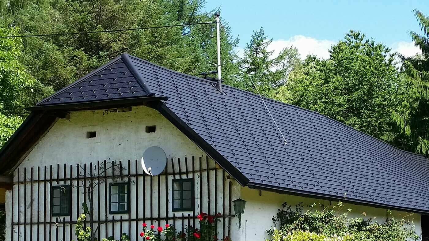 Ancienne ferme traditionnelle ; Le toit a été redécoré de bardeau en aluminium noir PREFA, avec des plantes grimpantes grimpant sur la façade.