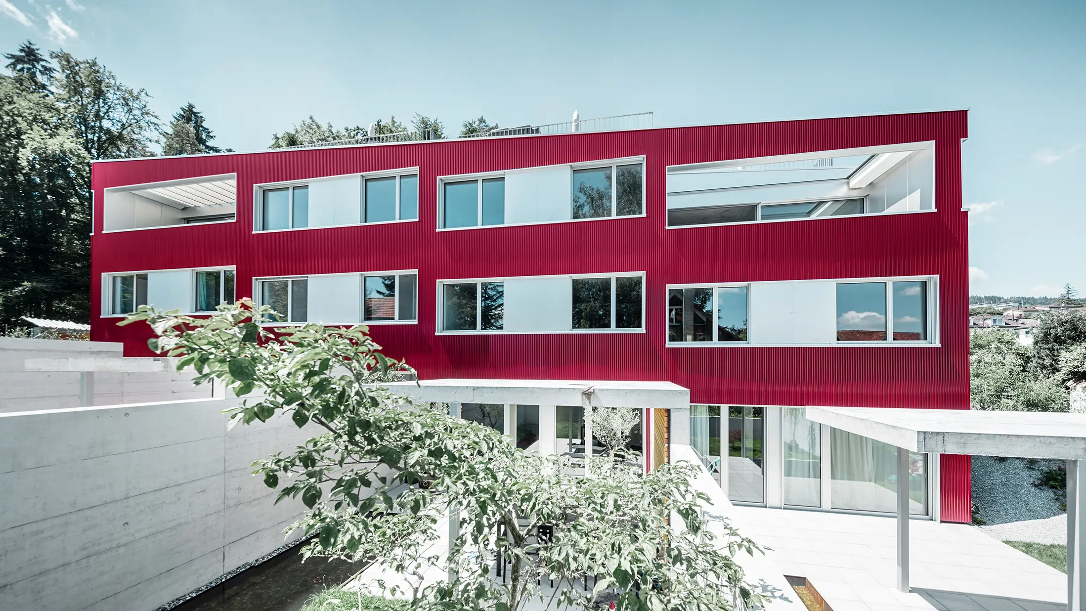 Complexe résidentiel à toit plat et façade de balcons avec profil sinus  bordeaux de PREFA 