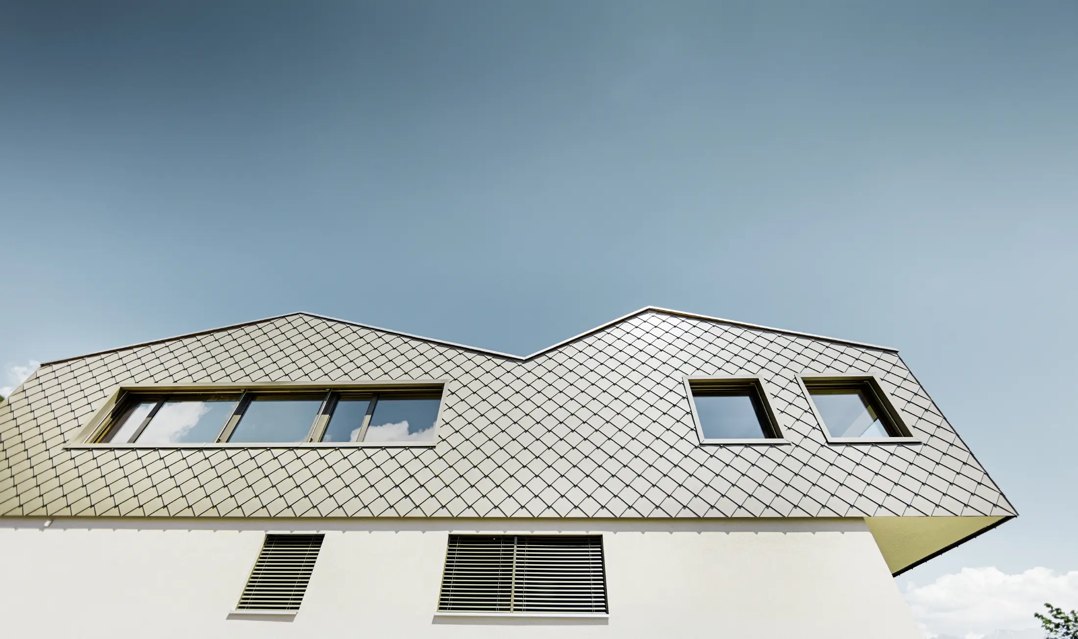 Maison individuelle moderne au milieu des vignobles de la vallée du Rhône avec 4 toits différents et galerie ouverte avec une façade en losanges couleur bronze