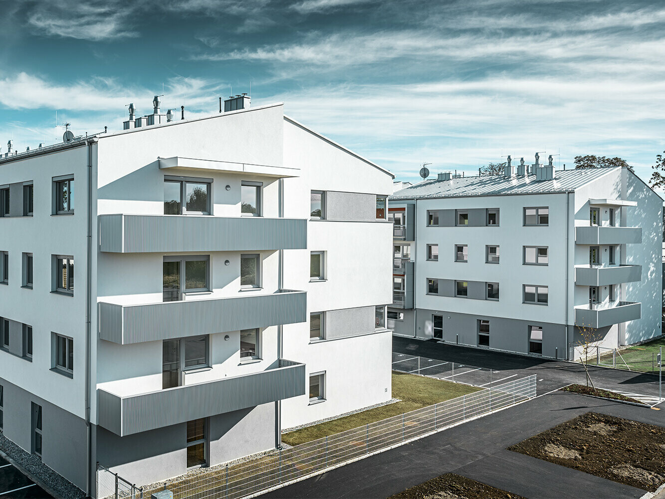 Complexe résidentiel moderne avec façade blanche et balcons en profil triangle  PREFA couleur argent métallisé