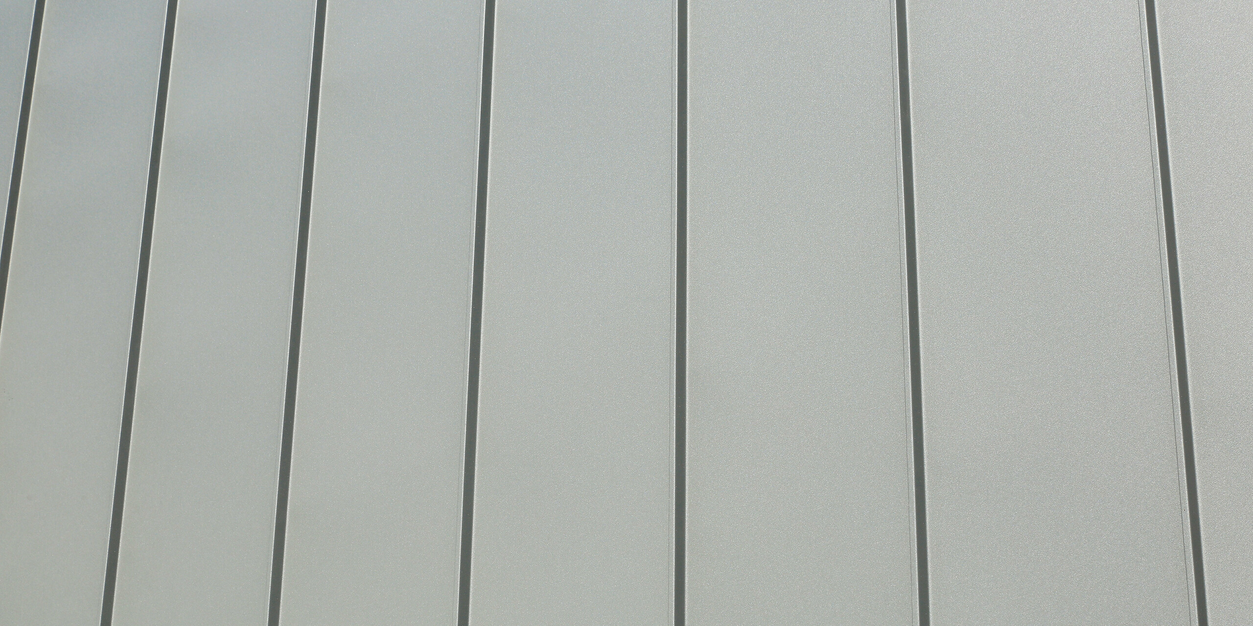 Le joint debout PREFALZ en gris souris s'étend sur les façades et les toits à pignon d'un lotissement mitoyen à Mundolsheim. Les coques uniformes du bâtiment en aluminium créent une image globale harmonieuse.