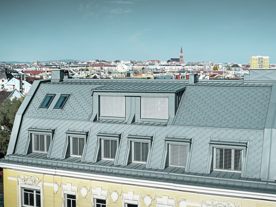 Nahaufnahme des denkmalgeschützten Hotels Schönbrunn in Wien, eingedeckt mit der PREFA Dachraute 29 x 29 und PREFALZ in der Farbe P.10 Hellgrau.