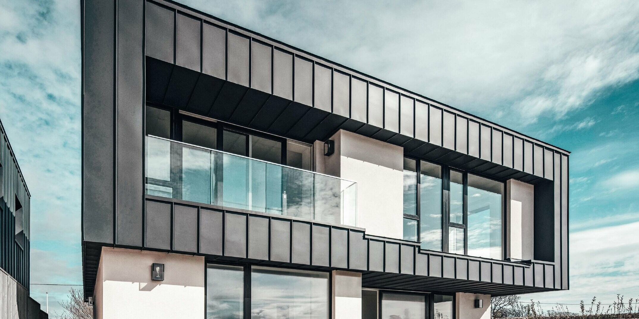 Maison mitoyenne avec toit plat, la façade à l'étage supérieur a été conçue à l'aide d'une façade à joint debout en PREFALZ couleur anthracite.