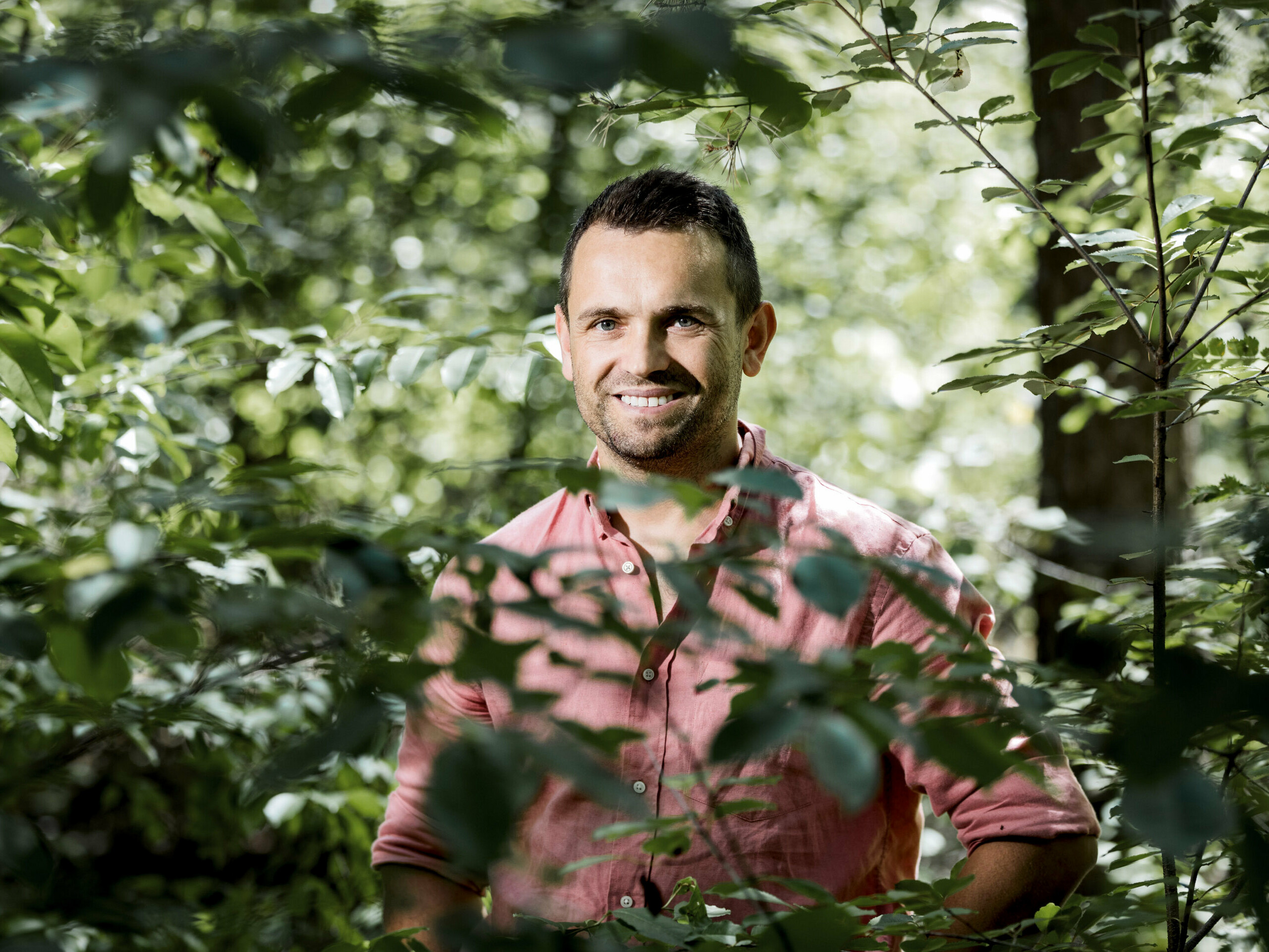 Portrait du propriétaire de la Boroteka, Rafał Stramski, souriant dans la forêt.