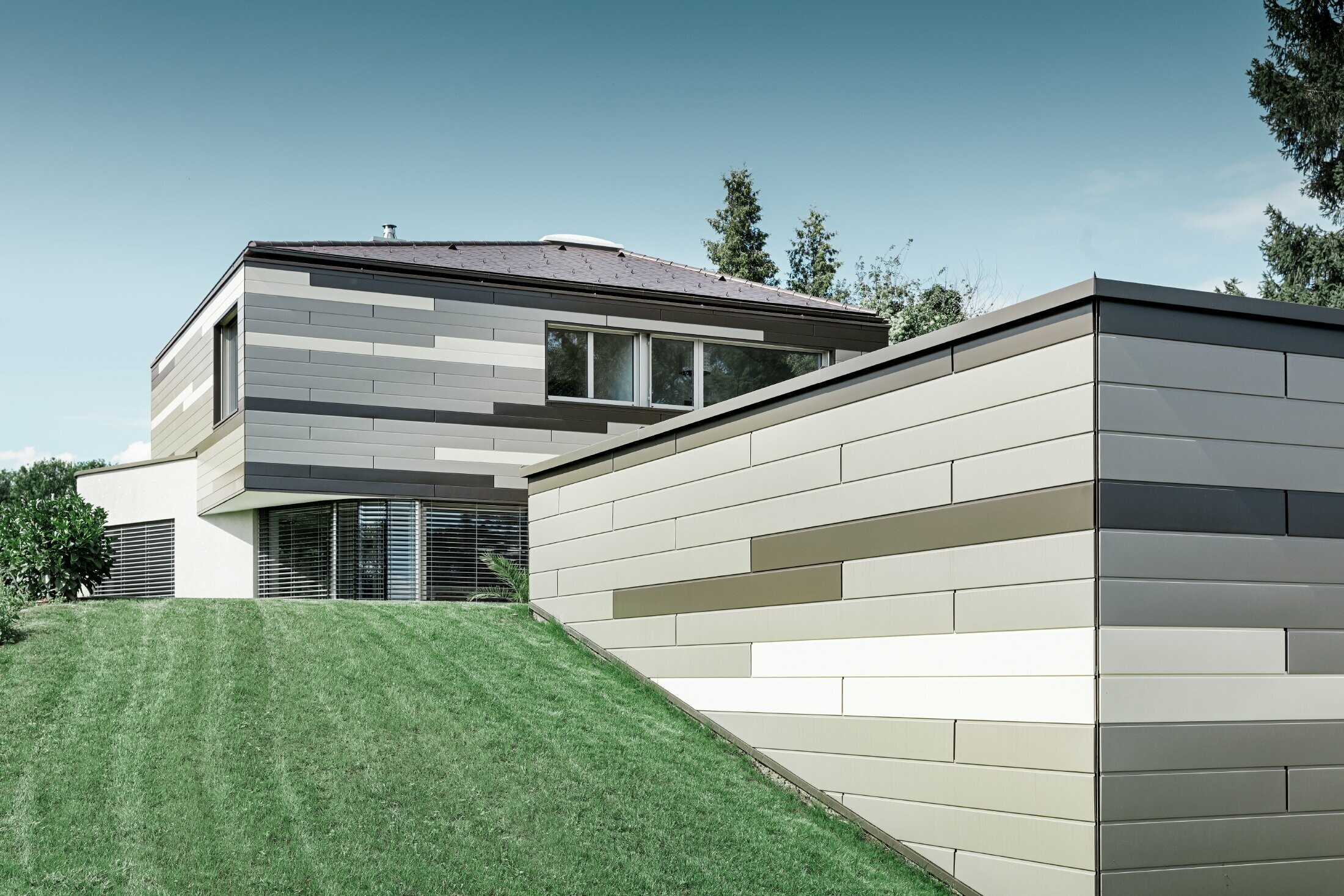 Maison individuelle moderne au toit plat avec terrasse couverte — Façade en aluminium au caractère très individuel réalisée avec des sidings PREFA de trois couleurs différentes (brun, bronze et ivoire clair)