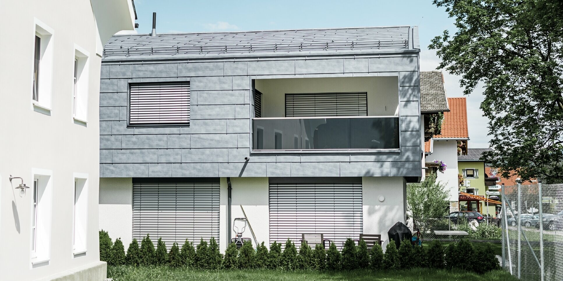 Bei dem Wohnhaus in Mieming wurde der gesamte obere Gebäudeteil mit dem PREFA Fassadenpaneel FX.12 in Steingrau verkleidet.