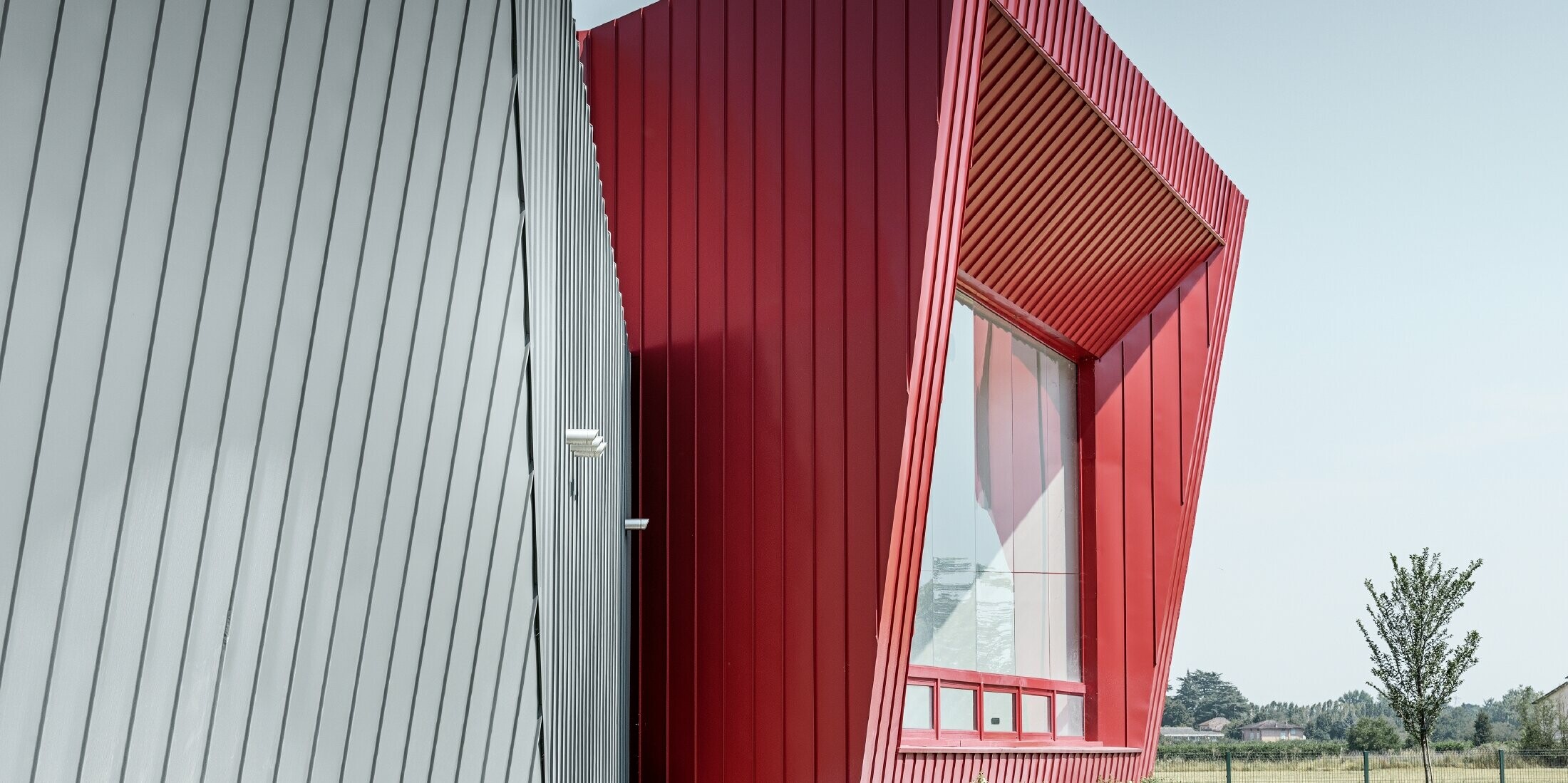 modernes Trainingscenter von Dieci in Montecchio Emilia, Italien, mit Tribüne mit Aluminiumfassade mit Prefalz in hellgrau und Falzonal in karminrot 