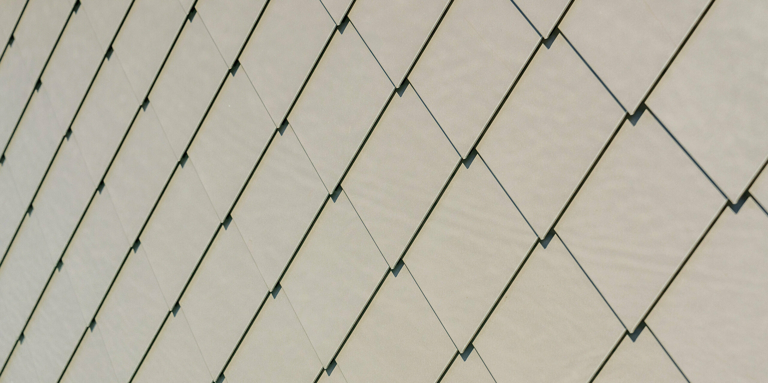 Detailaufnahme der PREFA Aluminiumfassade am Sporthotel Obereggen mit Wandraute 29 × 29 in der Farbe Bronze. Die präzise verlegten Rauten bilden ein ruhiges, geometrisches Muster mit feiner Oberflächenstruktur, die je nach Lichteinfall unterschiedlich wirkt. Der warme Bronzeton unterstreicht die hochwertige Ausstrahlung der modernen Architektur. Die langlebigen, witterungsbeständigen und wartungsarmen PREFA Aluminiumprodukte bieten nicht nur gestalterische Freiheit, sondern auch höchste Qualität und Sicherheit.