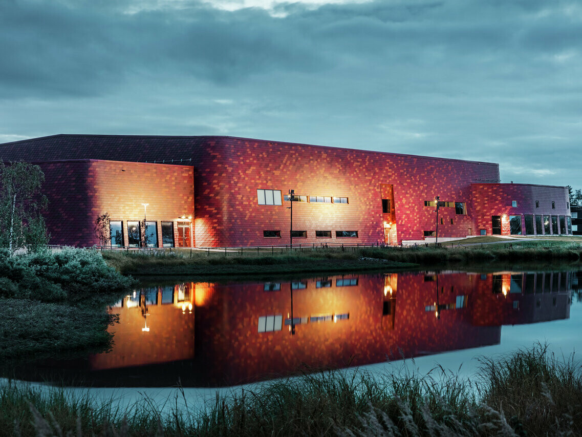 Photographie d'une patinoire en Suède. Les lumières du bâtiment sont allumées.