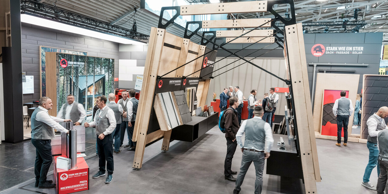 Belebter PREFA Messestand mit Messewänden mit den PREFA Aluminium Dachprodukten und Fassadenprodukten.