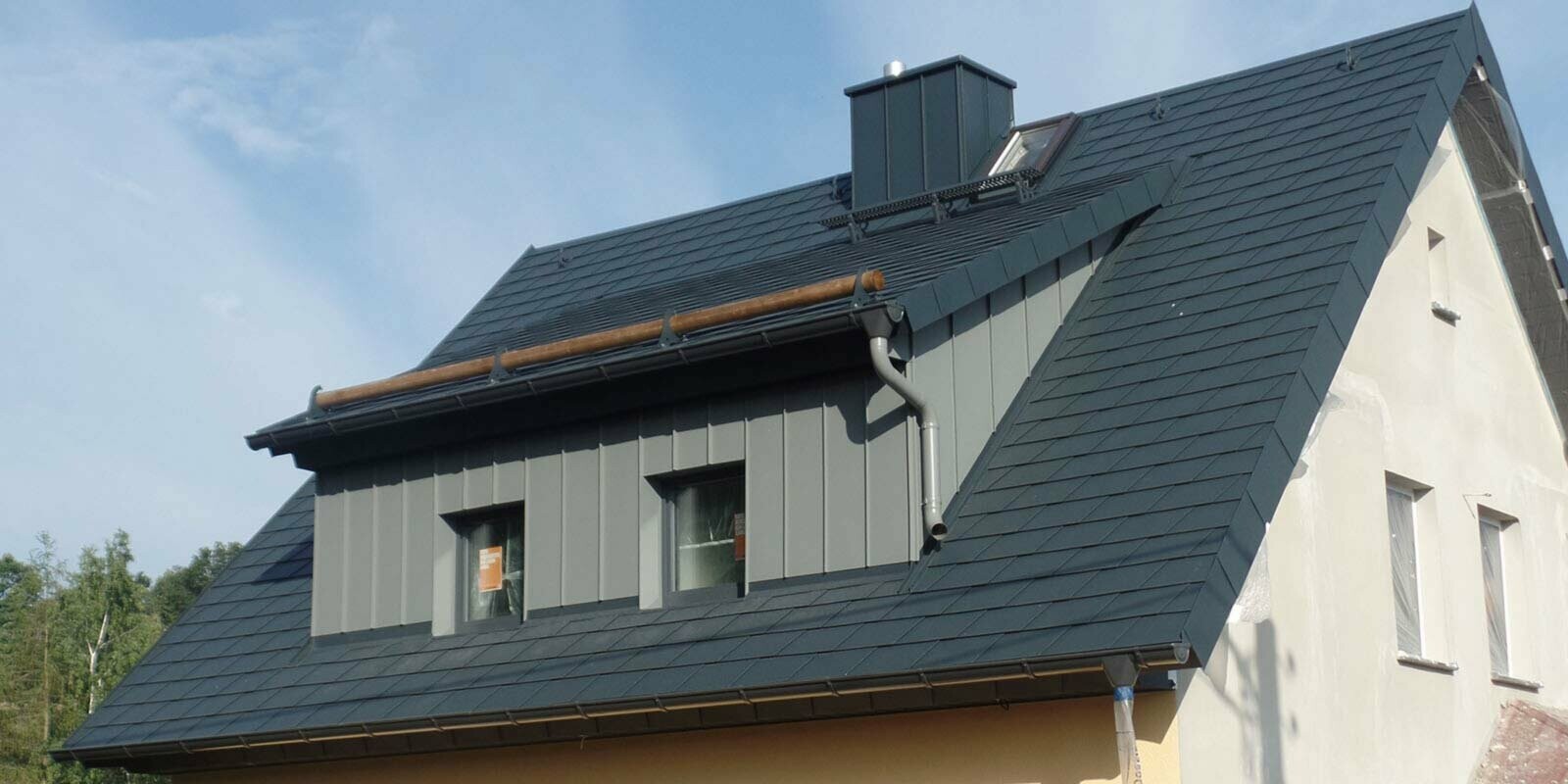 Bâtiment avec toit à deux pans et lucarne rampante, rénové à l’aide de bardeaux de toiture PREFA