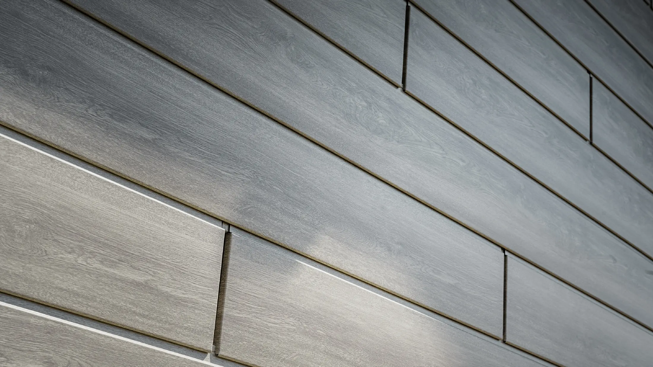 Gros plan sur la façade en aluminium PREFA Sidings. Les panneaux en aluminium ont été posés horizontalement et présentent un aspect bois - chêne gris.