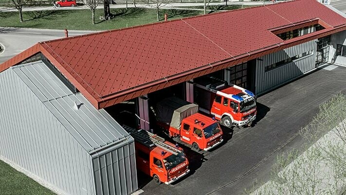 La caserne de pompiers de la société PREFA à Marktl avec sa toiture en losanges rouges doublée d’une solution à joints debout argent métallisé sur la façade et une partie de la toiture. Vous trouverez ici de plus amples informations sur les classes de réaction au feu.