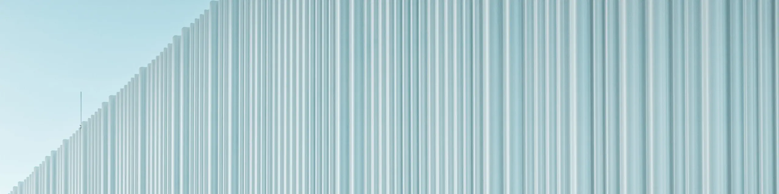 Une conception de façade spectaculaire avec le profil extrudé PREFA Sinus en aluminium de haute qualité habille le siège de l’entreprise LKW Walter à Vienne. La structure profilée, légèrement ondulée et disposée verticalement, crée un élégant effet de vagues générant de fascinants jeux de lumière. Alors que le bâtiment moderne séduit par son langage formel épuré, la découpe courbe de la façade apporte un contraste architectural fort et distinctif. Les profils en aluminium, durables et résistants à la corrosion, dotés d’une fixation invisible, garantissent une enveloppe extérieure haut de gamme et sans entretien.