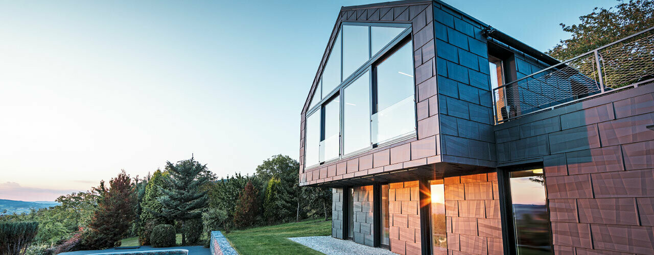 Modernes Einfamilienhaus ohne Dachvorsprung mit großen Fensterflächen und FX.12 Fassade in Anthrazit, bei Sonnenuntergang fotografiert.