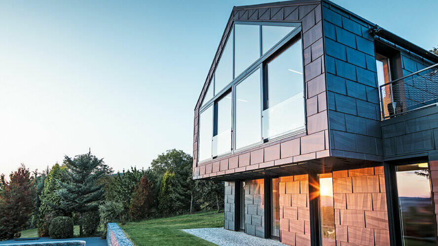 Modernes Einfamilienhaus ohne Dachvorsprung mit großen Fensterflächen und FX.12 Fassade in Anthrazit, bei Sonnenuntergang fotografiert.