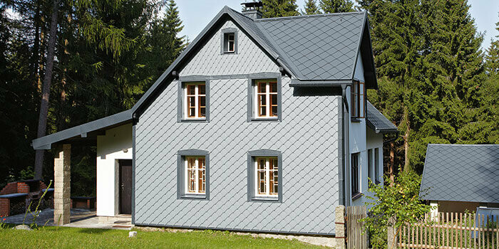 Maison individuelle avec système complet PREFA. La façade est recouverte de losanges de façade PREFA 29 couleur gris souris.