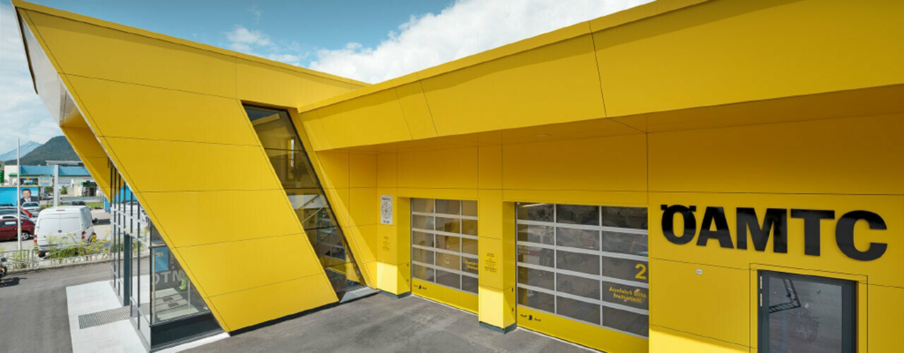 Base de l’ÖAMTC avec panneaux composites PREFA couleur jaune colza, installés comme façade suspendue et ventilée.