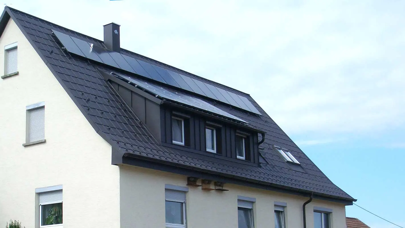 Toit récemment rénové à l’aide de tuiles PREFA couleur anthracite, la lucarne a été recouverte d’éléments Prefalz. Le toit est pourvu d’une installation photovoltaïque.