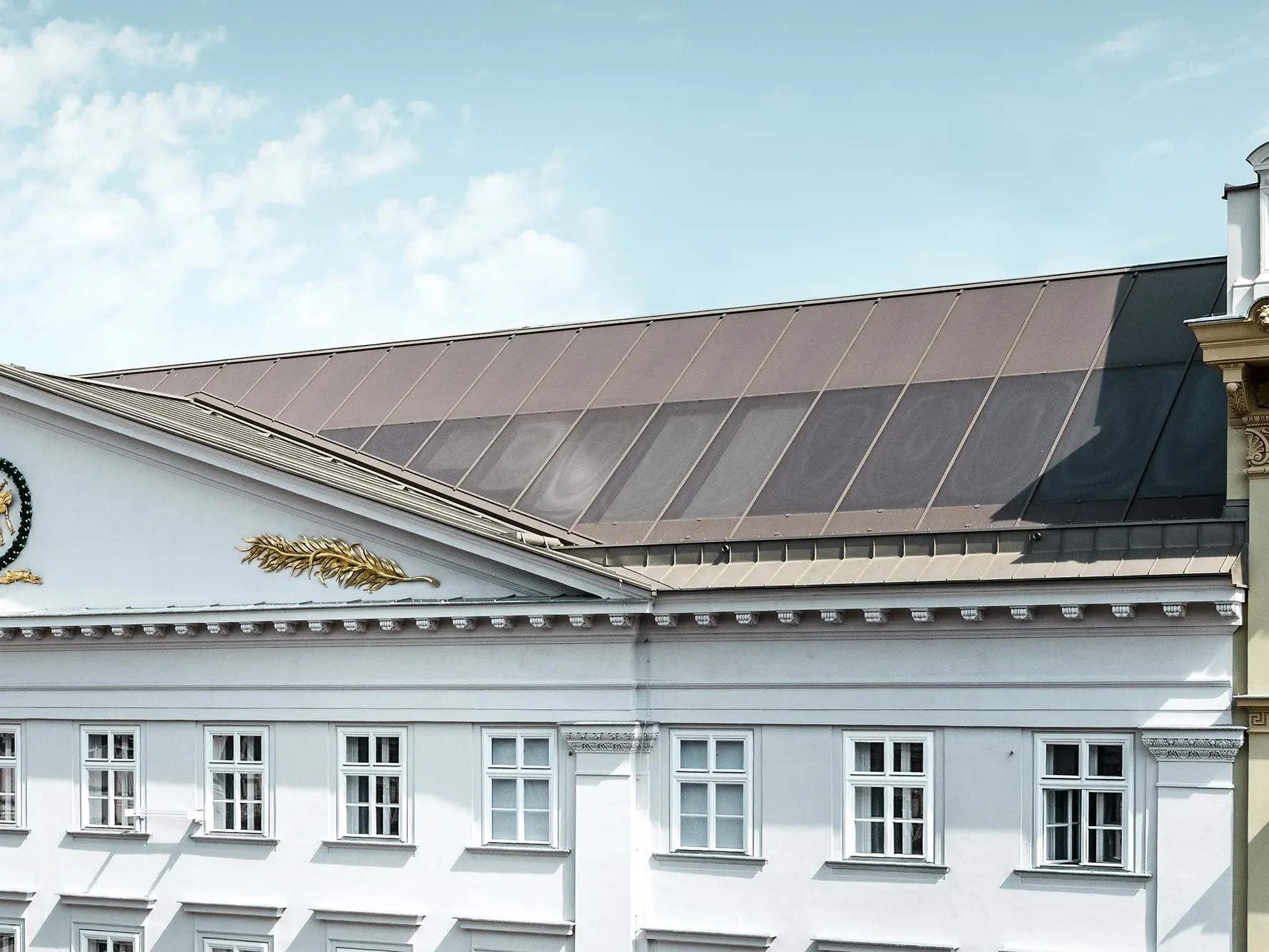 Detailansicht mit einem Teil der Fassade und dem Prefalz Dach samt siebbedruckten Gläsern.