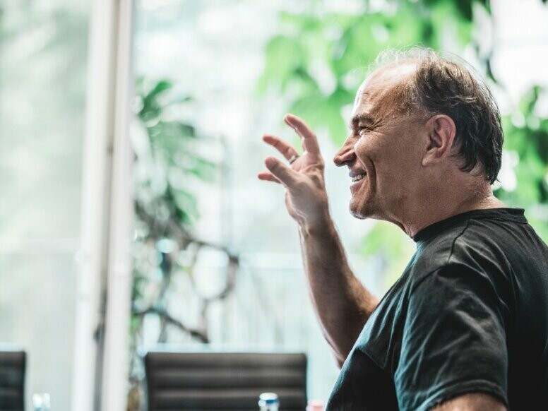 Vue de côté de l'architecte Lajos Hartvig qui se tient souriant devant le spectateur en observant les plantes.