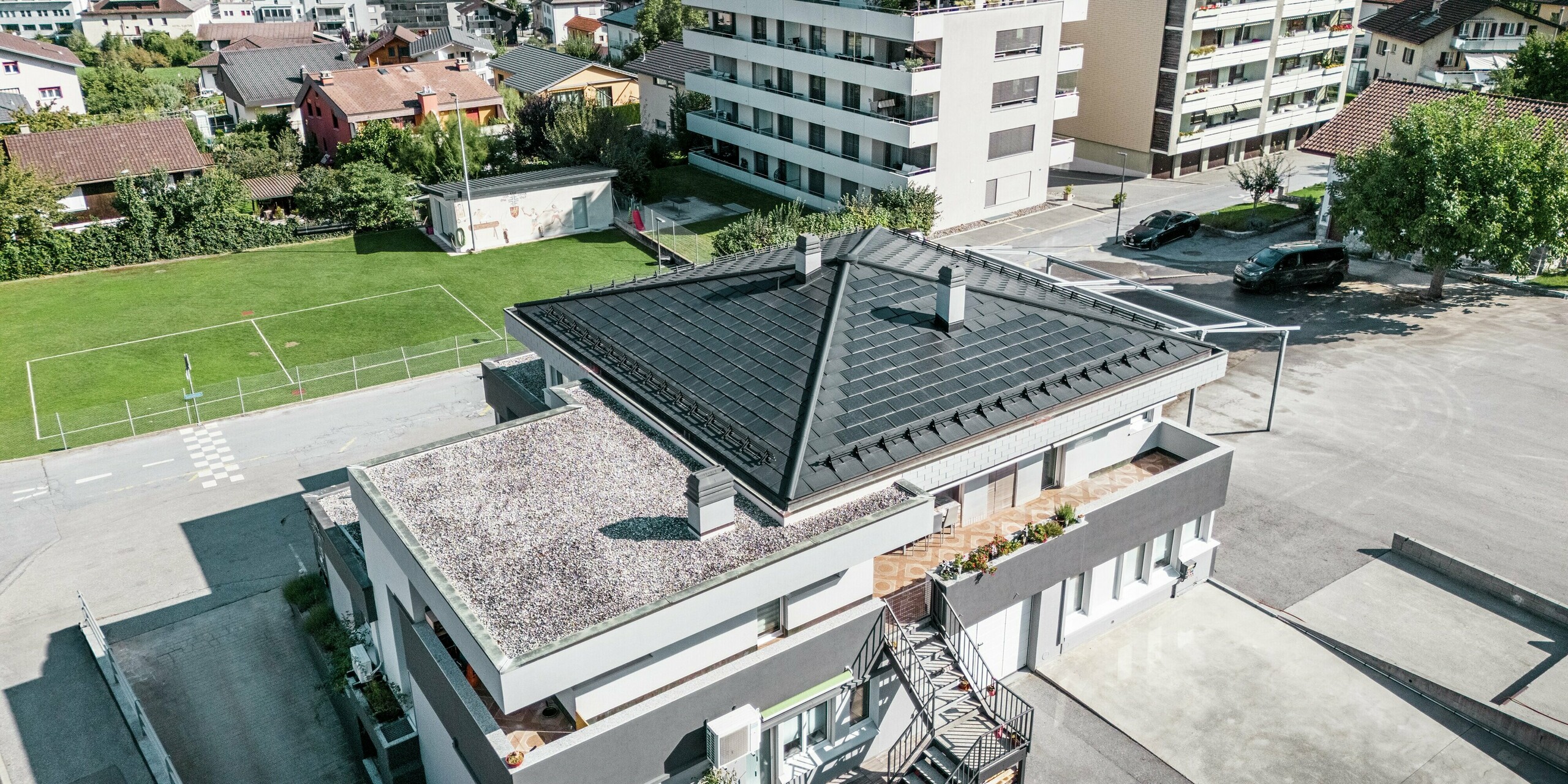 Das moderne Zeltdach der Weinkellerei Leukersonne in Susten (CH) mit PREFA Solardachplatte und Dachplatte R.16 in P.10 Schwarz - langlebig, witterungsbeständig und energieeffizient.