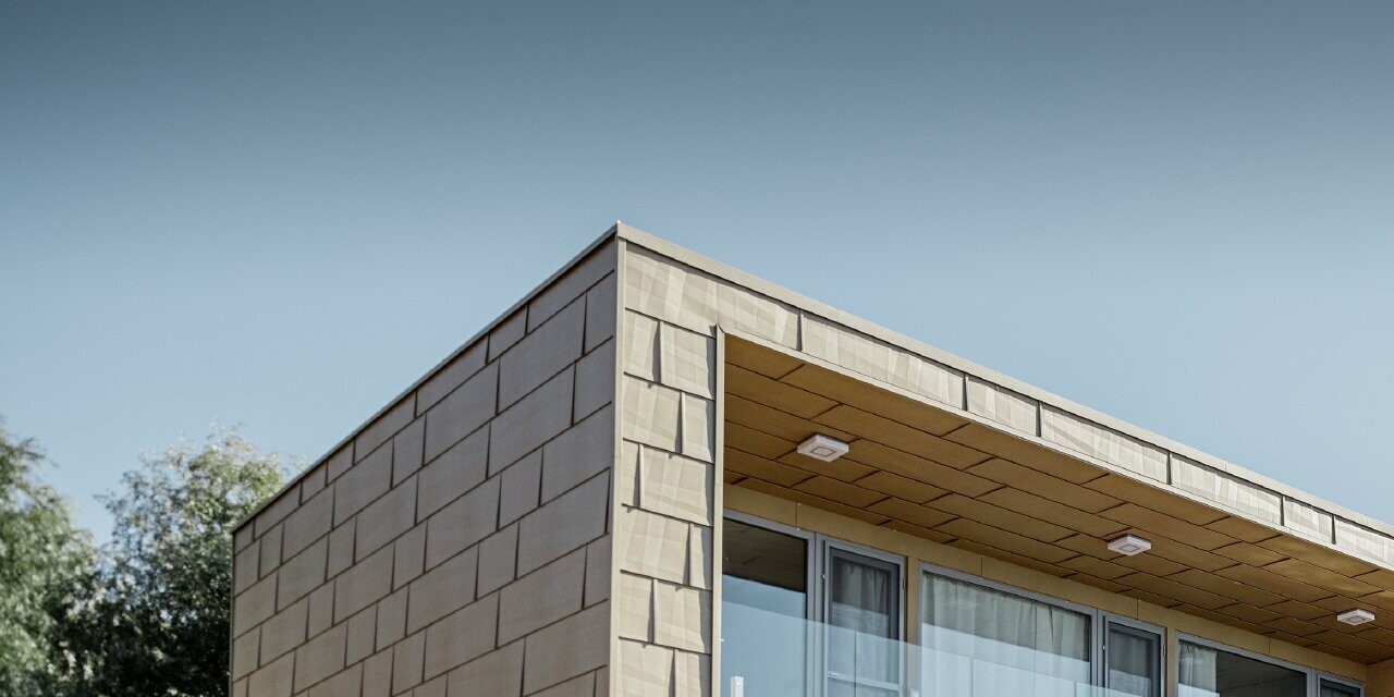 Maison secondaire moderne au toit plat et aux grandes baies vitrées donnant sur le lac — Façades en aluminium PREFA de couleur brun sable aux arêtes prononcées