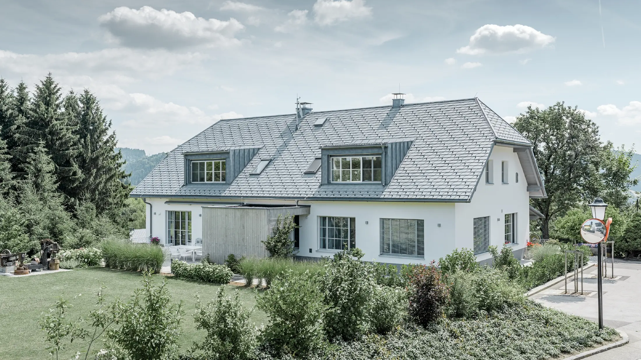 Rénovation d’un toit à demi croupe doté de deux lucarnes avec le léger bardeau de toiture PREFA couleur gris pierre.