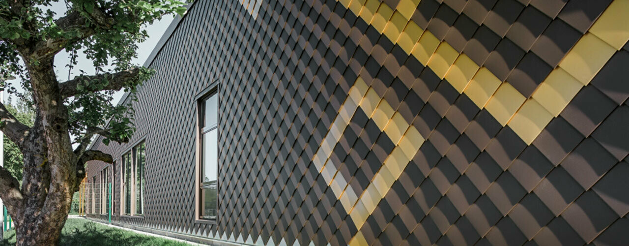 Façade avec losanges PREFA 20×20 couleur brun. Des losanges couleur or créent un motif sur la façade.