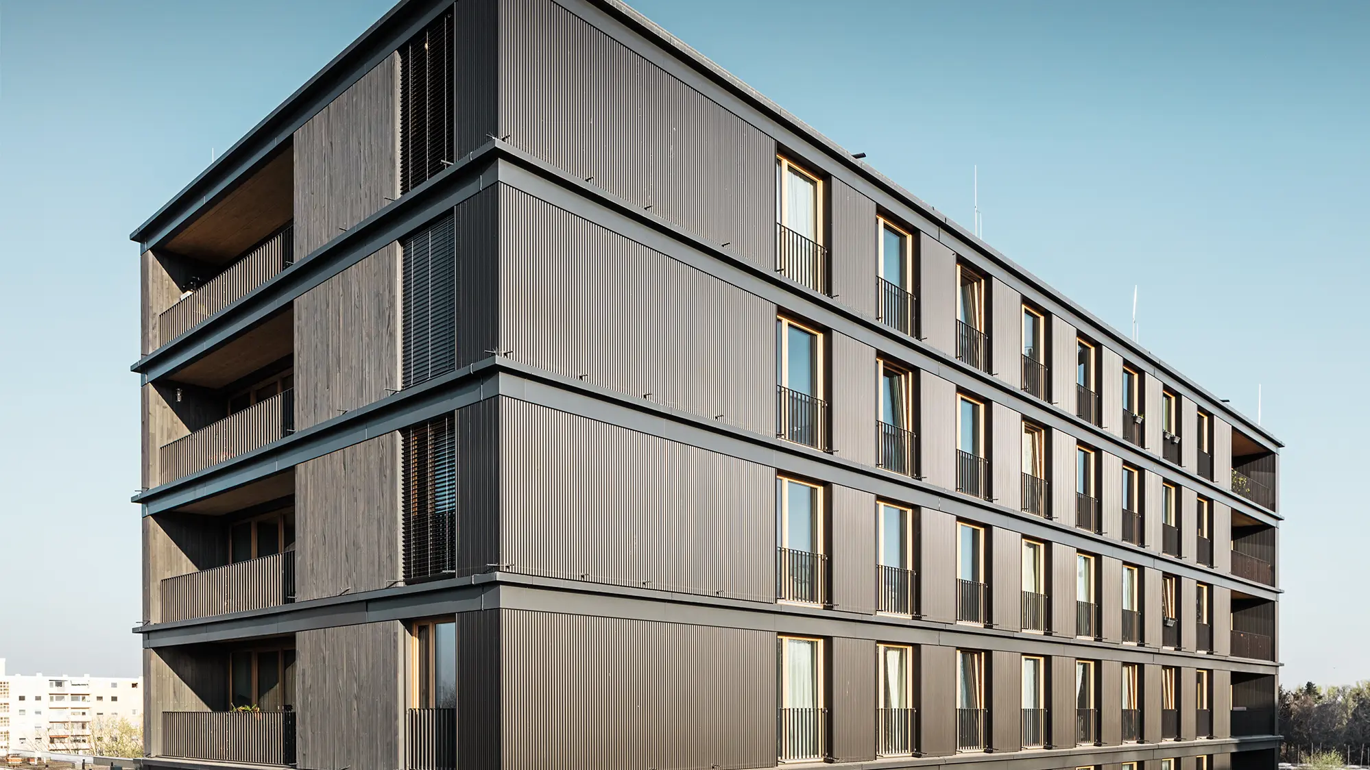 Das Wohn- und Geschäftshaus aus der Seitenperspektive: Die Strangpress-Welle von PREFA und die Holzfassade sind kaum voneinander zu unterscheiden.