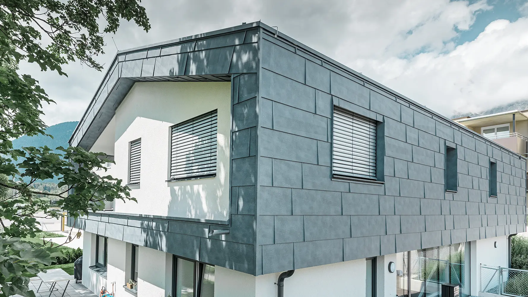 Modernes Einfamilienhaus ohne Dachvorsprung; Die obere Etage wurde mit PREFA Fassadenpaneelen FX.12 in Steingrau verkleidet, der Rest der Fassade wurde weiß verputzt.