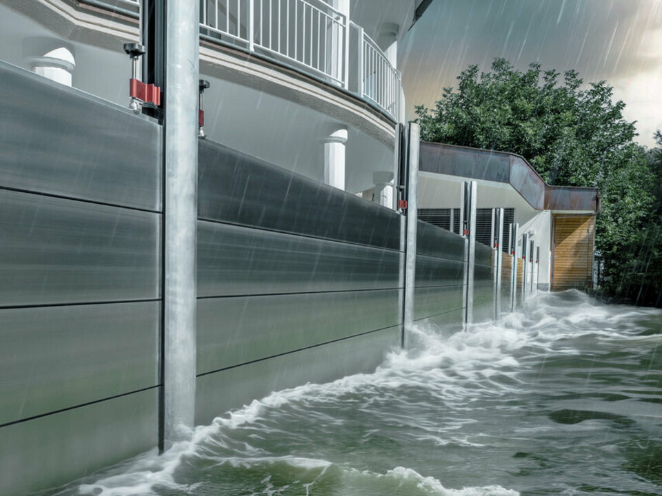 Gros plan sur la protection contre les crues PREFA en aluminium, qui résiste toujours aux inondations catastrophiques et protège la maison individuelle en arrière-plan.