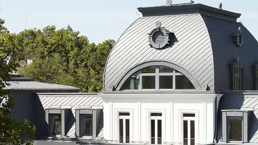 Toit mansardé du bâtiment classé monument historique avec coupole, rénové à l’aide de losanges de toiture PREFA et de Prefalz en P.10 gris souris