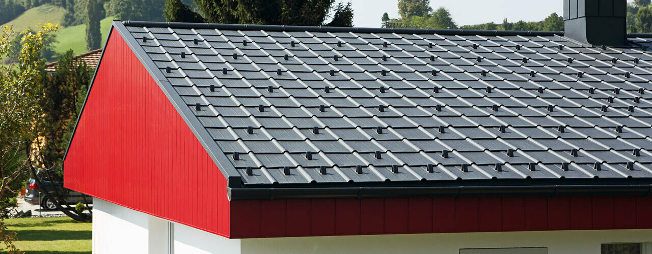 Giebelverkleidung in Rot mit PREFA Aluminium Siding, vertikal verlegt. Am Dach wurde die PREFA Dachplatte in P.10 Anthrazit verlegt.