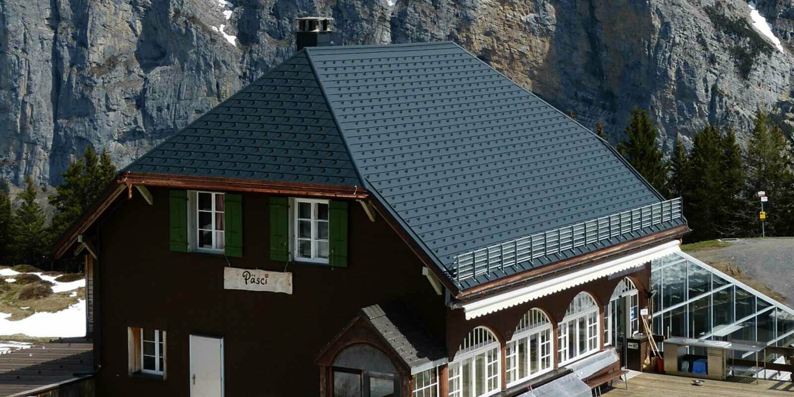 Rénovation de la toiture à deux pans en croupe d’un refuge de montagne, à l’aide de bardeaux de toiture PREFA et arrêts de neige