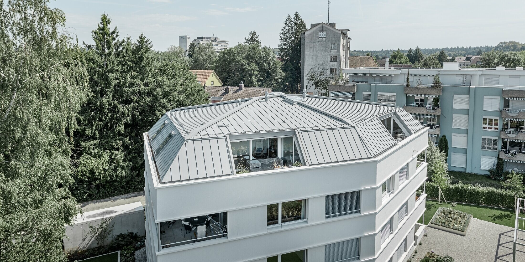 Dach eines Mehrparteienhauses eingedeckt mit dem PREFA Prefalz in Patina grau mit  Loggia.