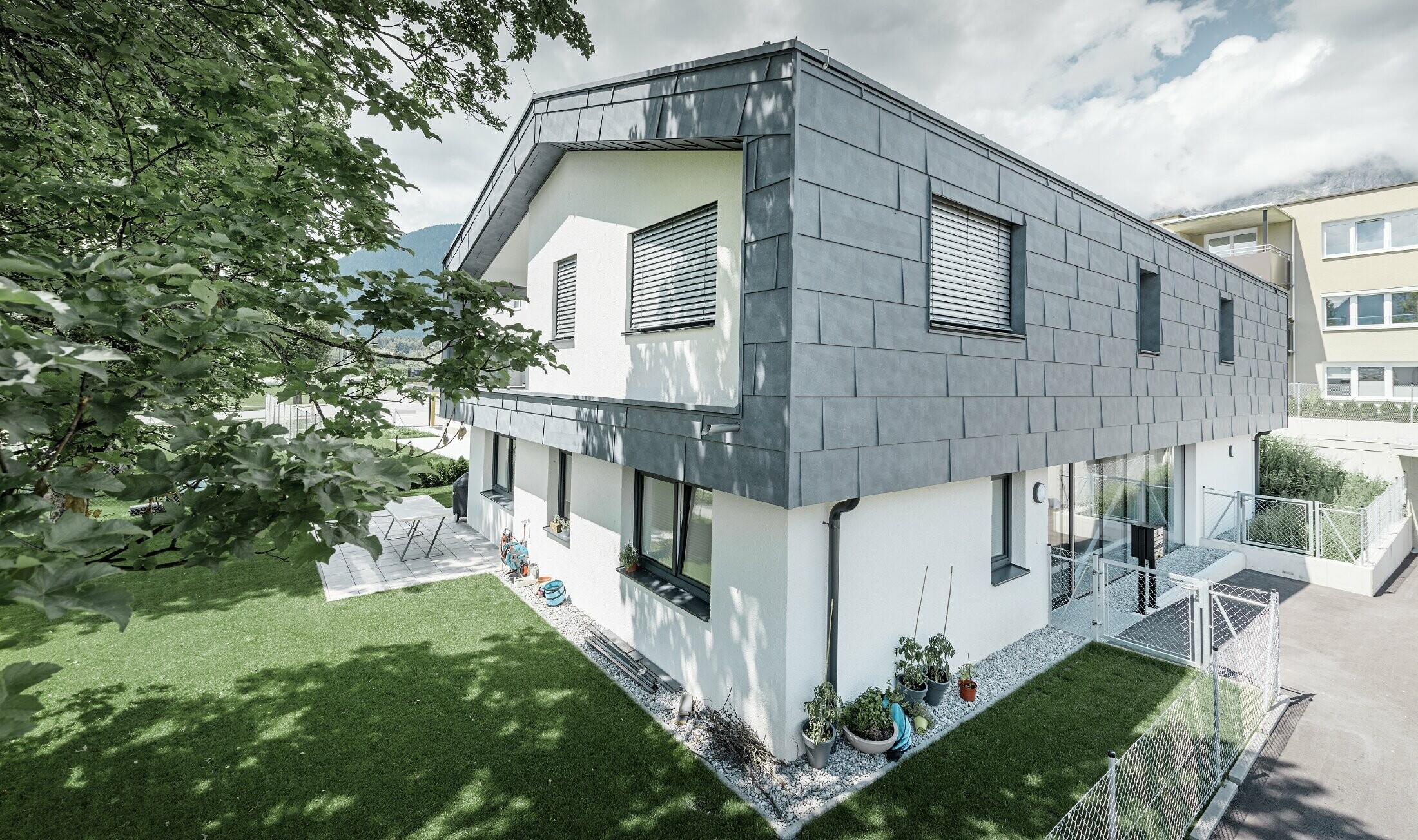 Moderne Aufstockung eines Wohnhauses mit flachem Satteldach und ohne Dachvorsprung; Die Fassadenverkleidung wurde mit dem PREFA Fassadenpaneel FX.12 in Steingrau.