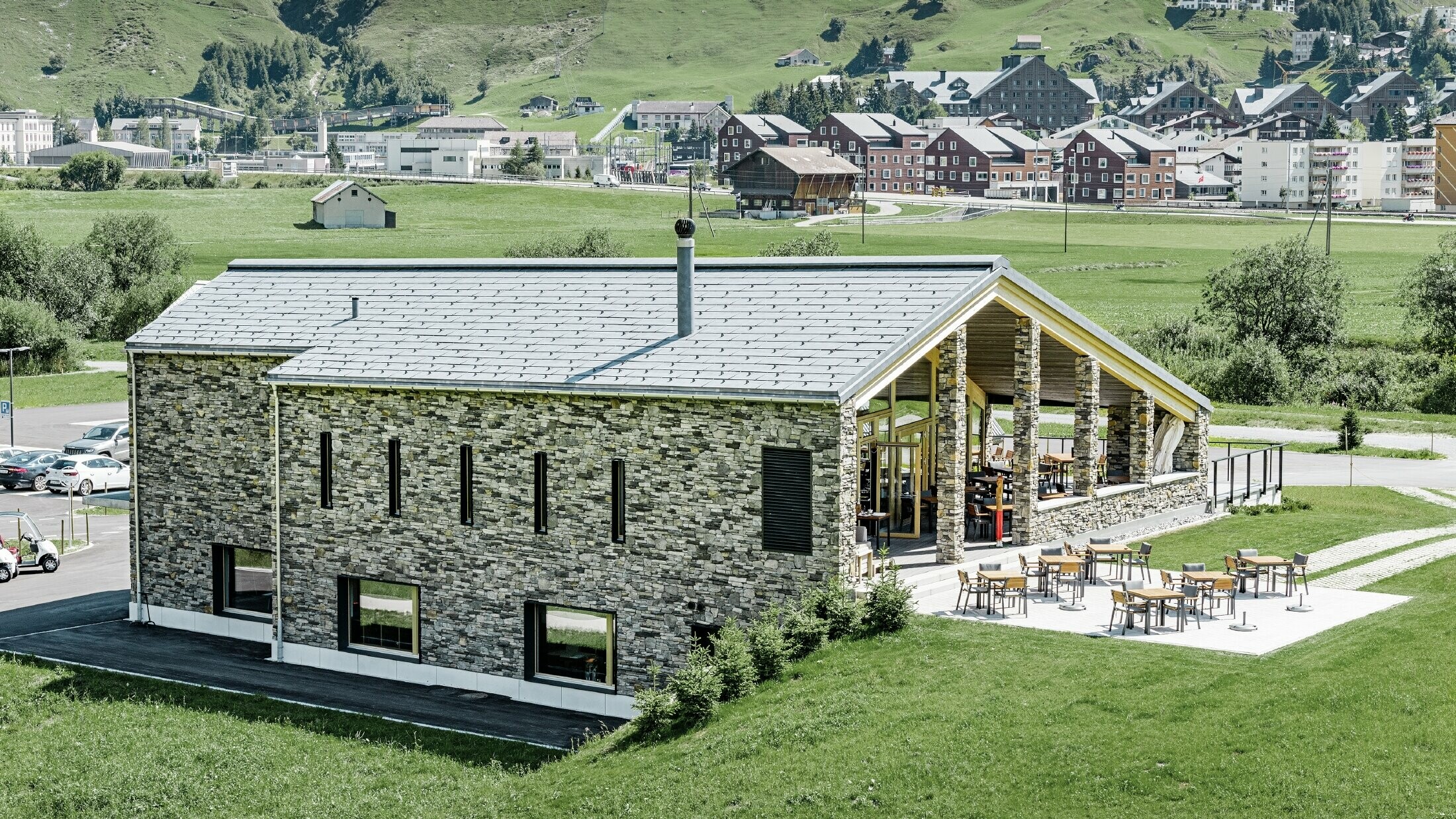 Modernes Club Haus des Golfplatzes in Andermatt mit Steinfassade und PREFA Dachpaneel FX.12 aus Aluminium in steingrau