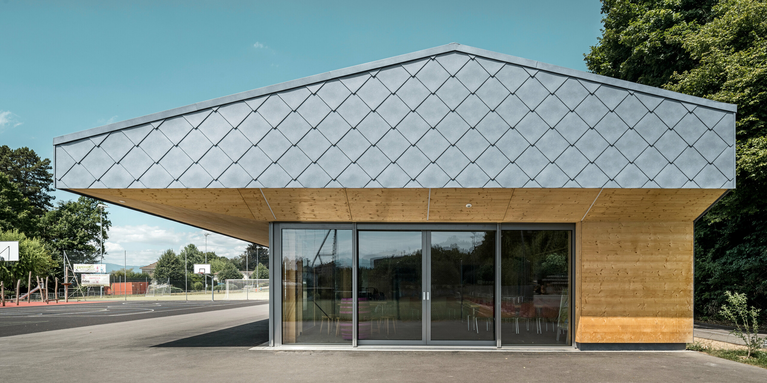 Das Gebäude einer Sportanlage in Prilly in der Schweiz wurde mit der PREFA Dach- und Wandraute 44x44 in P.10 Steingrau verkleidet. Auf dem Dach wurde großflächig eine Photovoltaikanlage montiert. 