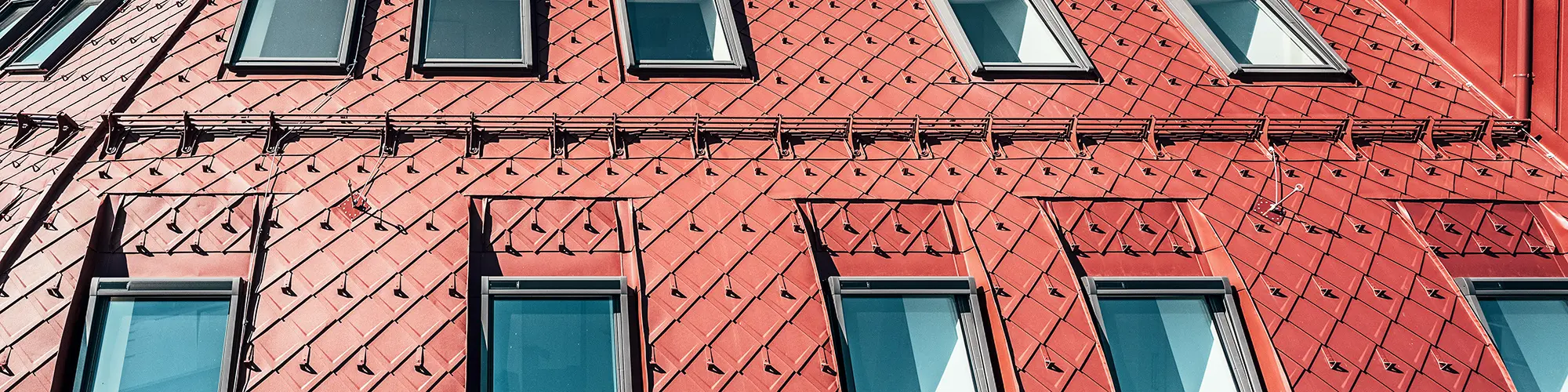 Detailansicht der auffälligen Dachlandschaft aus oxydroten Aluminiumrauten.