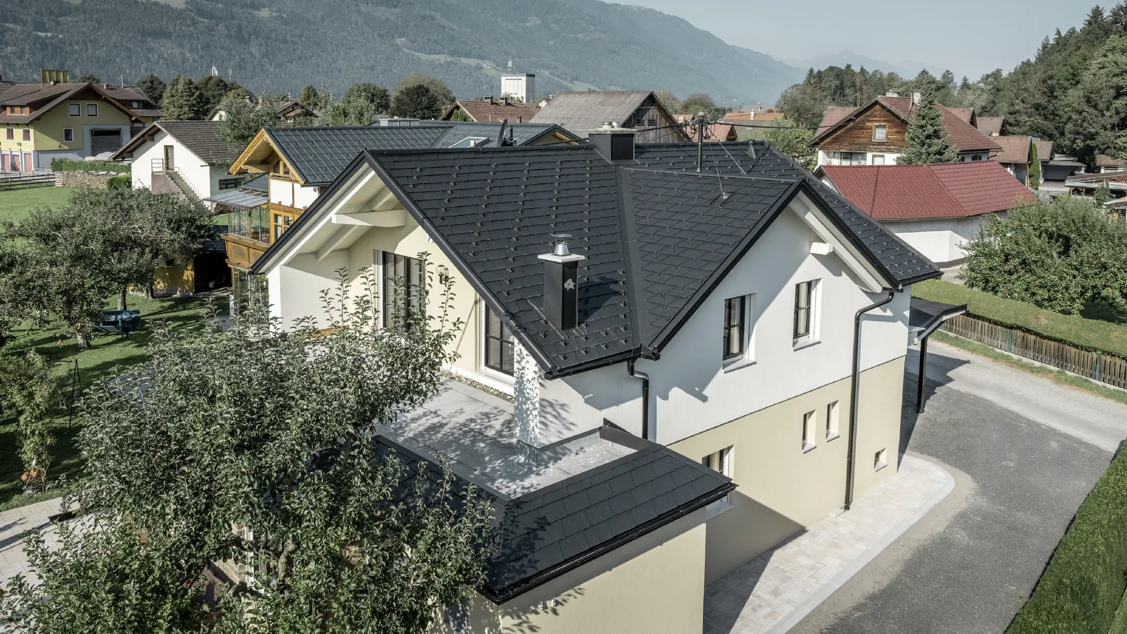 Maison individuelle traditionnelle avec toit en bâtière et grande lucarne, récemment rénovée. La toiture est recouverte de bardeaux noirs PREFA.