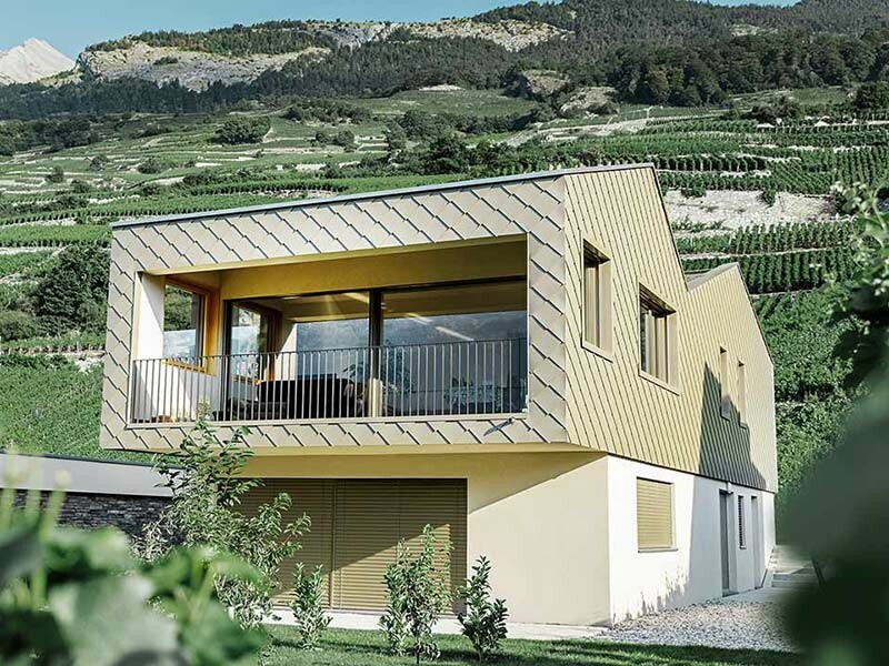 Modernes Einfamilienhaus mit doppeltem Satteldach, verkleidet mit PREFA Wandraute in Bronze