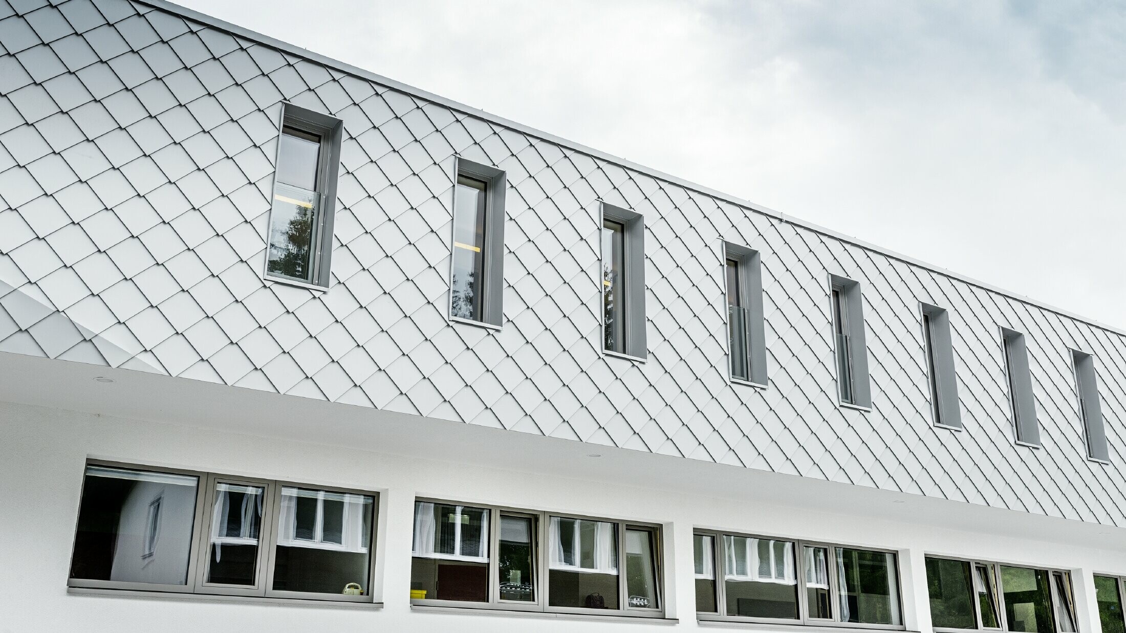 Neu gebauter Kindergarten in Kaprun mit einer modernen Aluminium Fassade mit der PREFA Wandraute in prefaweiss