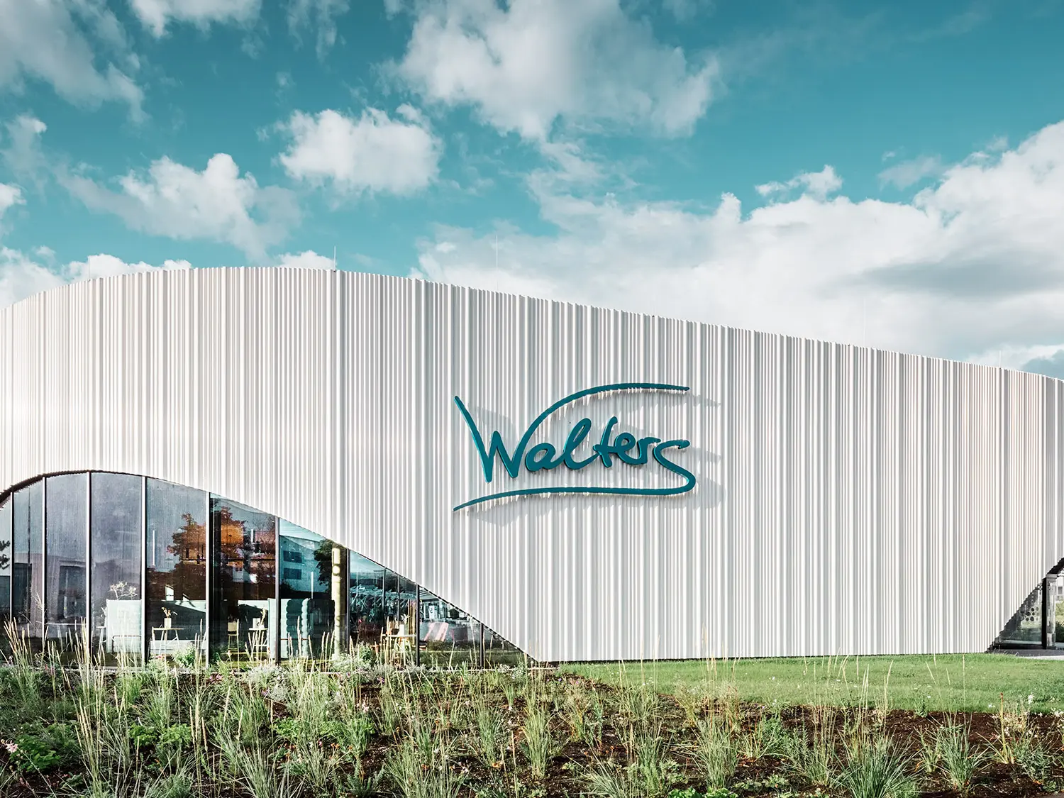 Vue normale du restaurant Walters avec l'une de ses fenêtres en arc de cercle au milieu d'un environnement verdoyant.