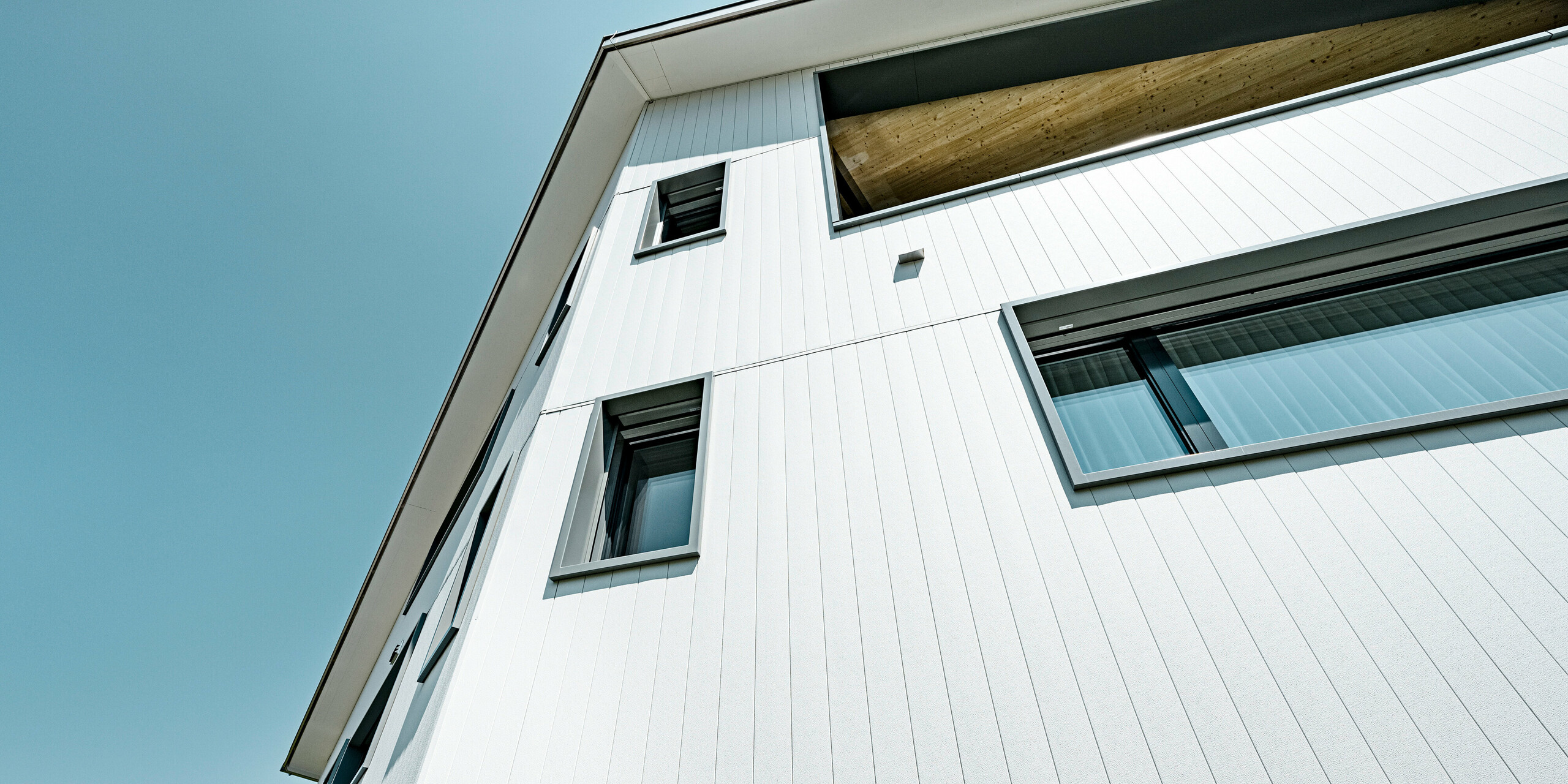 Sidings PREFA en gris pierre P.10 et blanc Prefa P.10 sur les façades de deux immeubles d'habitation voisins à Weissbad, en Suisse.