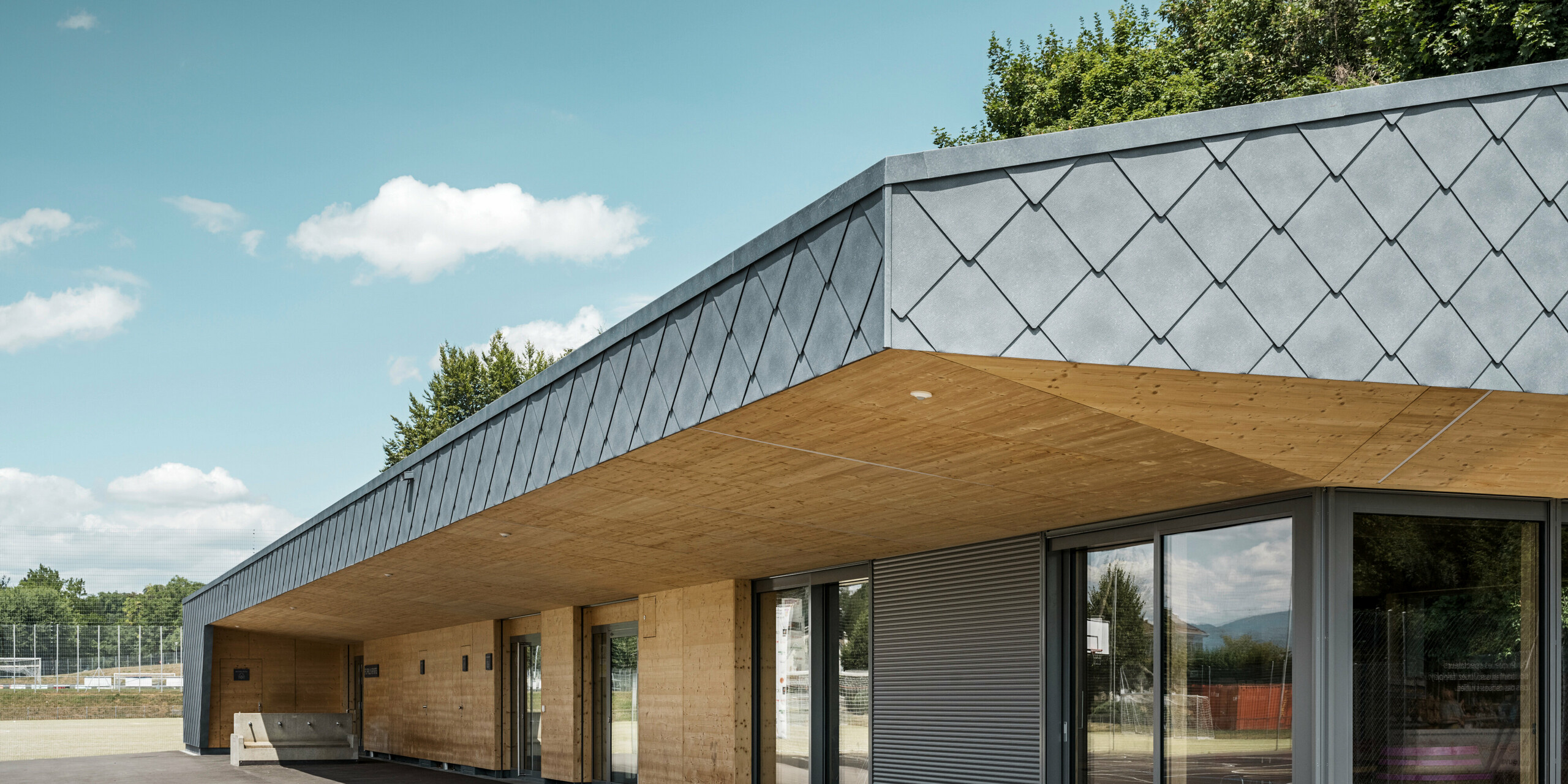 Das Gebäude einer Sportanlage in Prilly in der Schweiz wurde mit der PREFA Dach- und Wandraute 44x44 in P.10 Steingrau verkleidet. Auf dem Dach wurde großflächig eine Photovoltaikanlage montiert. 
