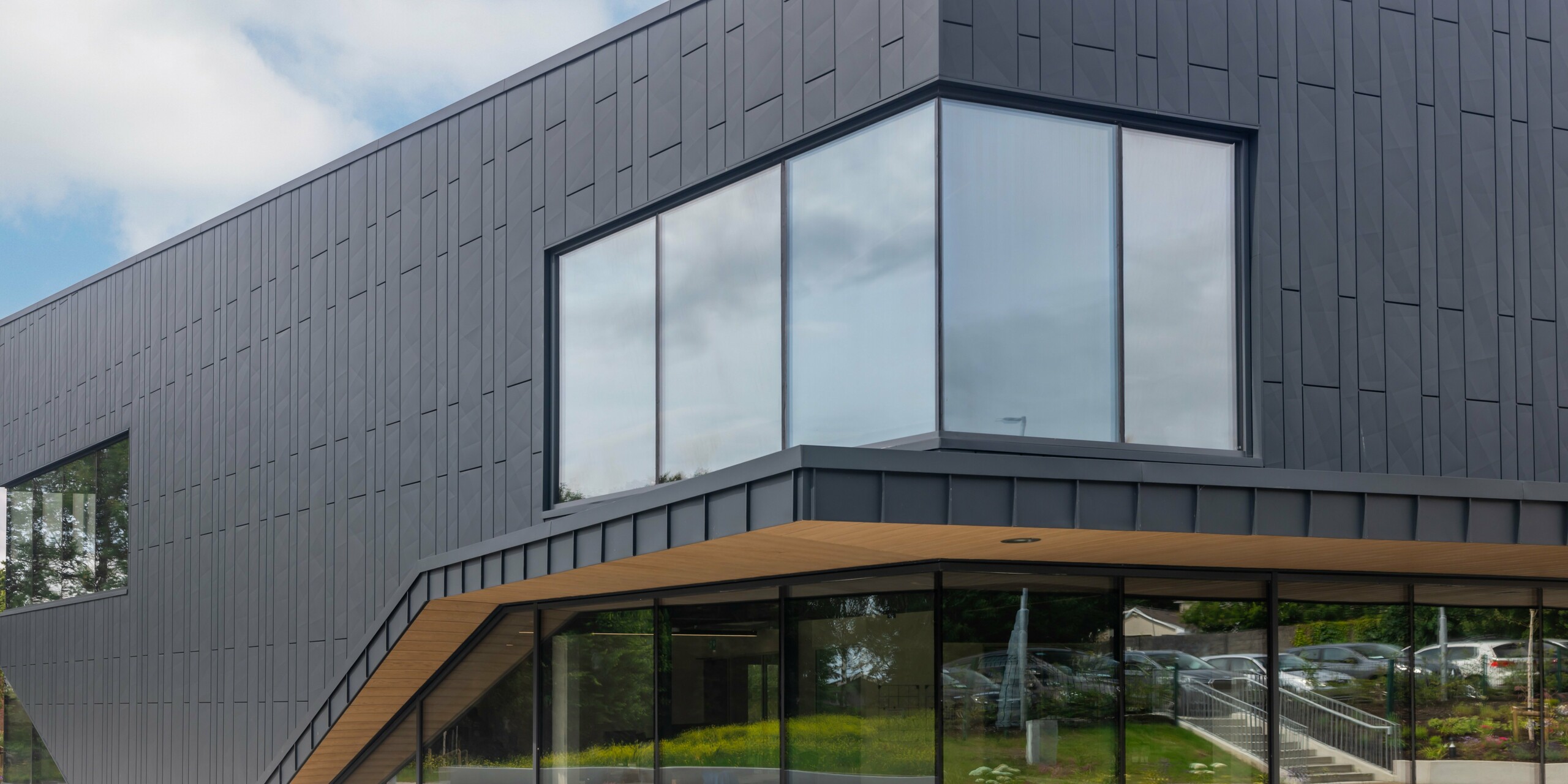 Vue détaillée de la façade moderne du bâtiment CREW à Galway, Irlande, conçue avec les panneaux de façade PREFA Siding.X et PREFALZ dans la couleur P.10 anthracite. La fenêtre d'angle frappante souligne les lignes claires et l'architecture innovante du bâtiment. Le revêtement en aluminium de couleur anthracite confère à la propriété une élégance intemporelle et démontre la haute qualité des produits en aluminium PREFA.