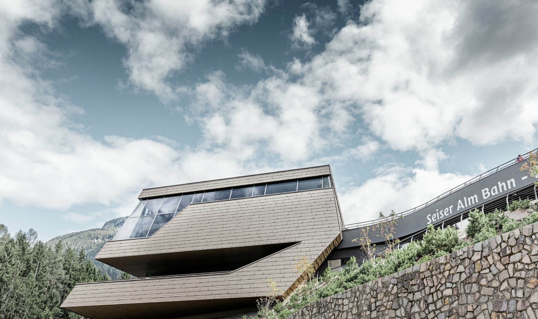 neu gestaltete Talstation der Umlaufbahn Seiser Alm, ähnlich der Dolomiten im Hintergrund mit unregelmäßigen Kanten und Oberflächen mit einer Aluminium Fassade in braun von PREFA