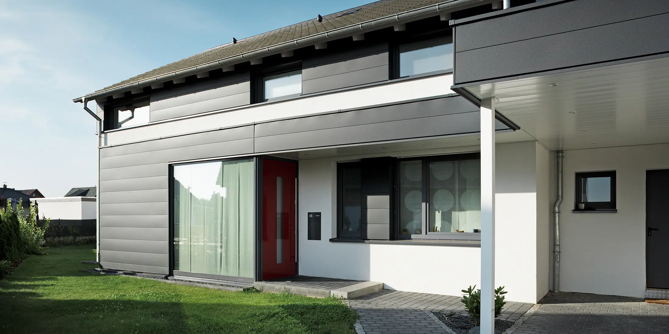 Rückseite eines modernen Einfamilienhauses in Isenbüttel, ausgestattet mit PREFA Aluminium-Sidings in P.10 Anthrazit – ein perfektes Zusammenspiel von Funktionalität und Ästhetik. Die großzügigen Fenster sorgen für ein optisches Highlight und lichtdurchflutete Innenräume.